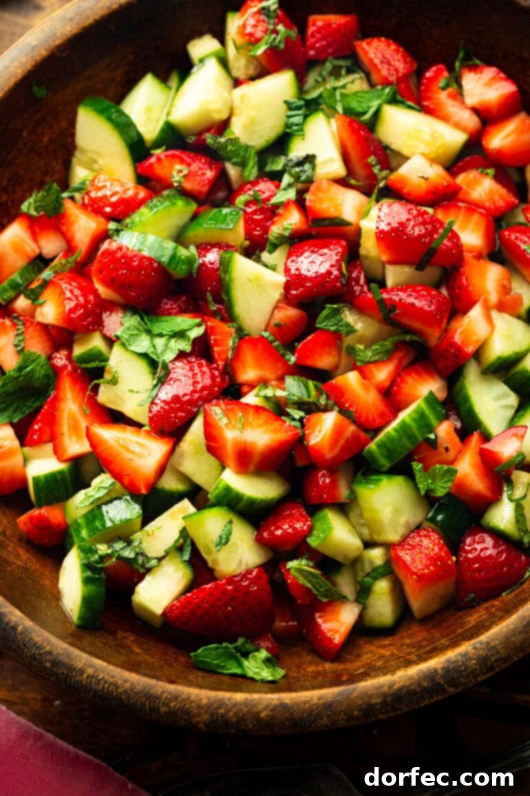 Honey Balsamic Strawberry Cucumber Salad 6 A large wooden mixing bowl filled to the brim with vibrant strawberry cucumber salad, ready to be served.