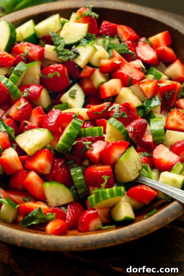 Honey Balsamic Strawberry Cucumber Salad 7 A close-up of a refreshing cucumber and strawberry salad, beautifully tossed with honey balsamic vinegar dressing and fresh mint.