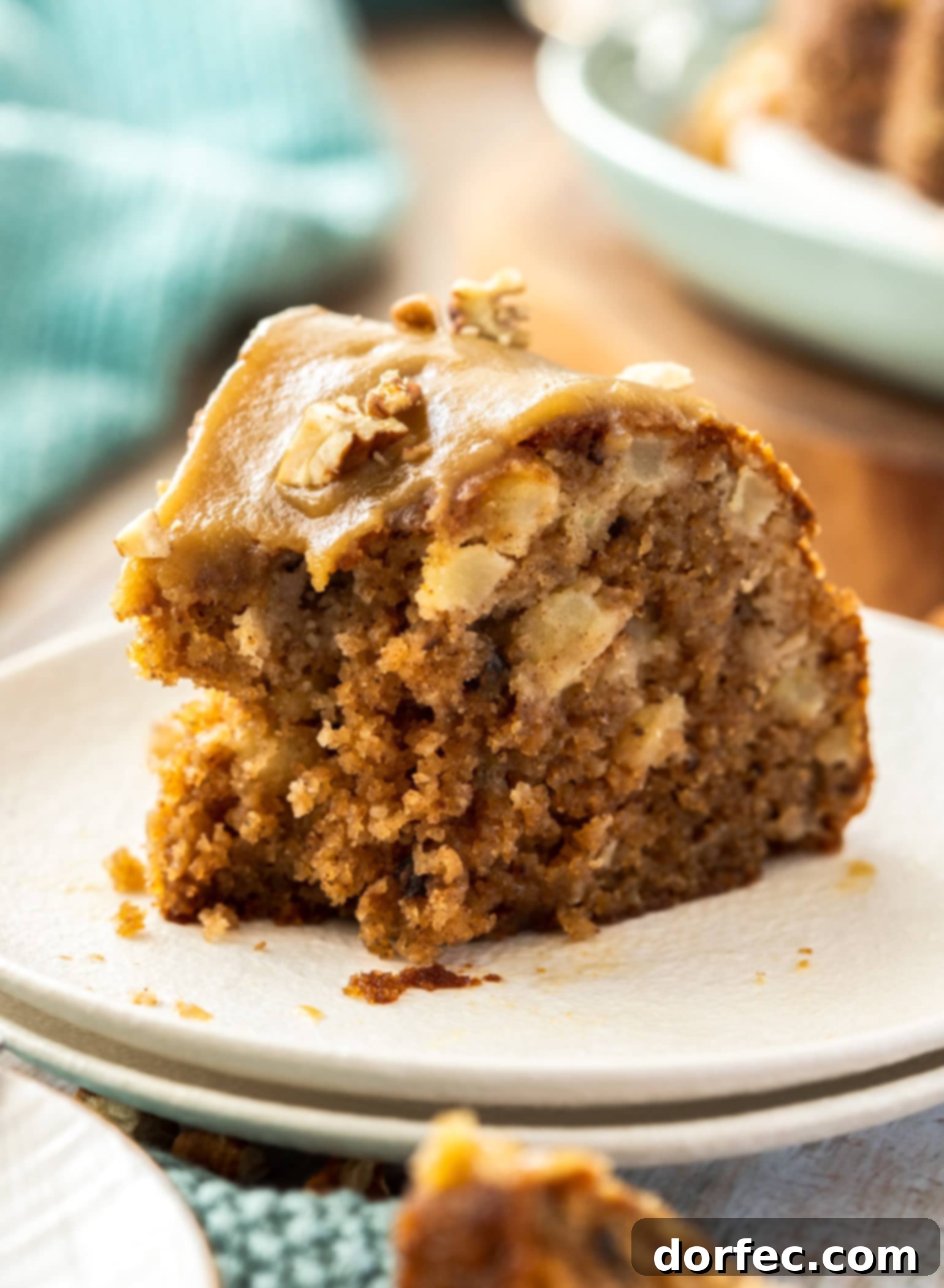 A close-up shot of a perfect slice of fresh Pecan Apple Bundt Cake, revealing its moist texture and the delicious blend of apples and pecans, with a bite taken out, enticing taste buds.