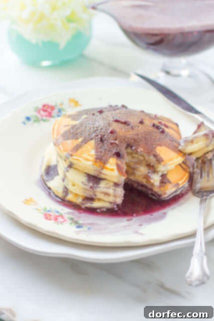 A bottle of rich, creamy marionberry syrup next to a stack of golden pancakes, ready to be enjoyed.