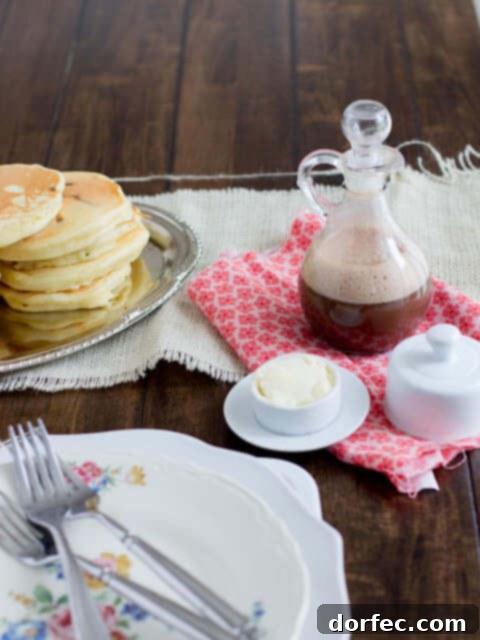 A tall glass of creamy chocolate syrup with a spoon, ready to be enjoyed with breakfast.