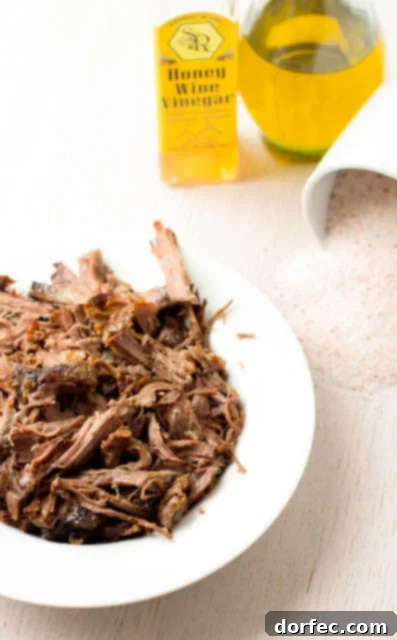 Perfectly cooked, tender shredded beef ready to be served or used in various dishes like BBQ sandwiches and tacos.