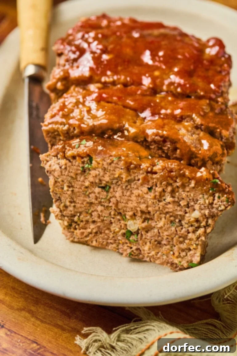 A beautifully sliced meatloaf presented on a white serving tray, showcasing its tender texture and rich, savory glaze.
