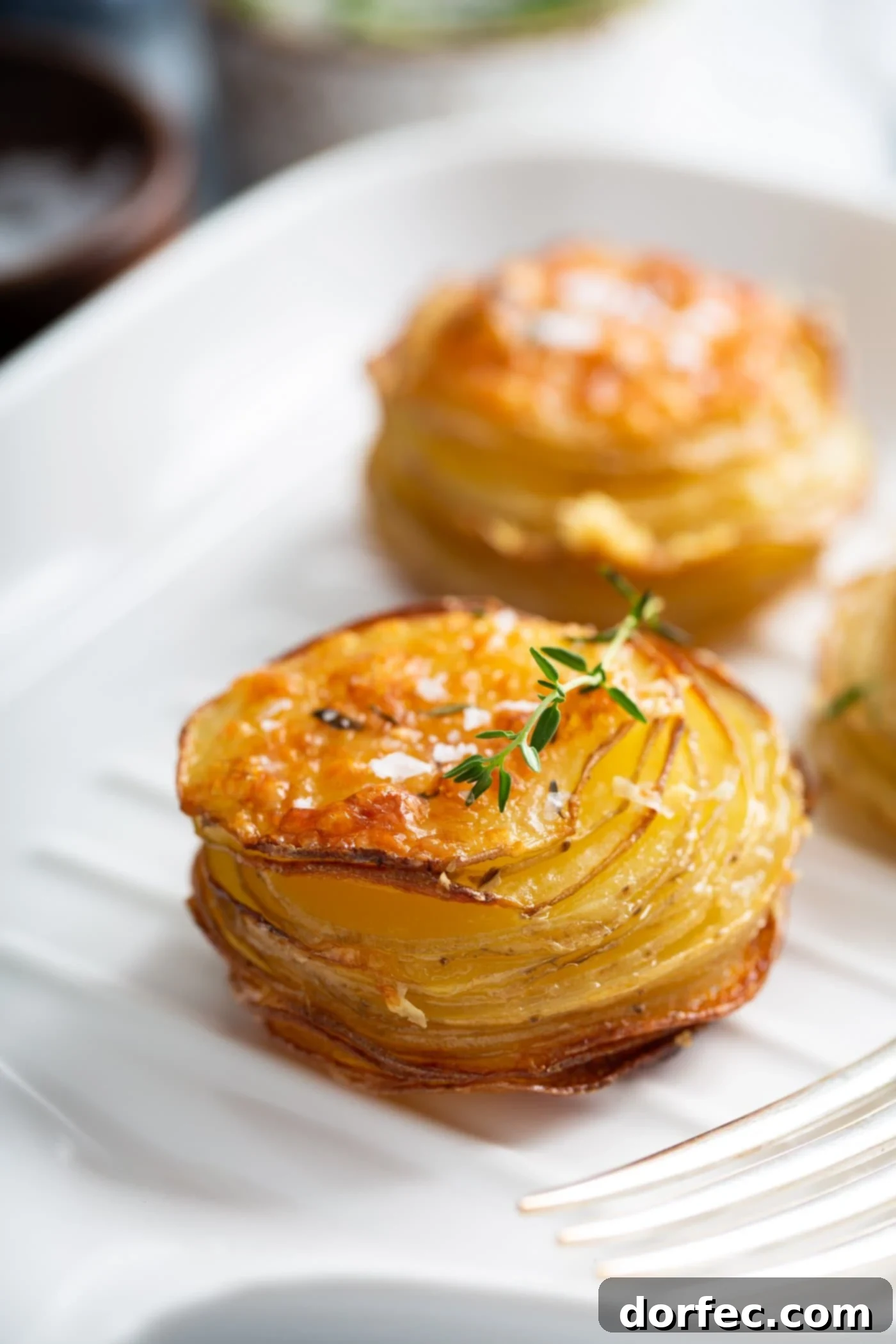 Two stacks of gruyere potatoes. They are shaped like muffins and they are baked to a golden brown.