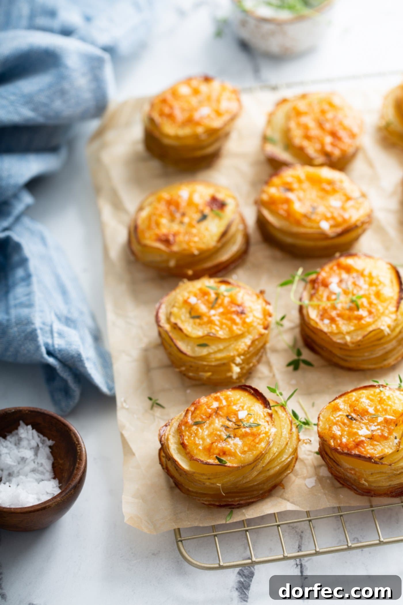 Gruyer potatoes that are baked to a golden brown. They look like little muffins. They are sitting on parchment paper on a wire cooling rack.
