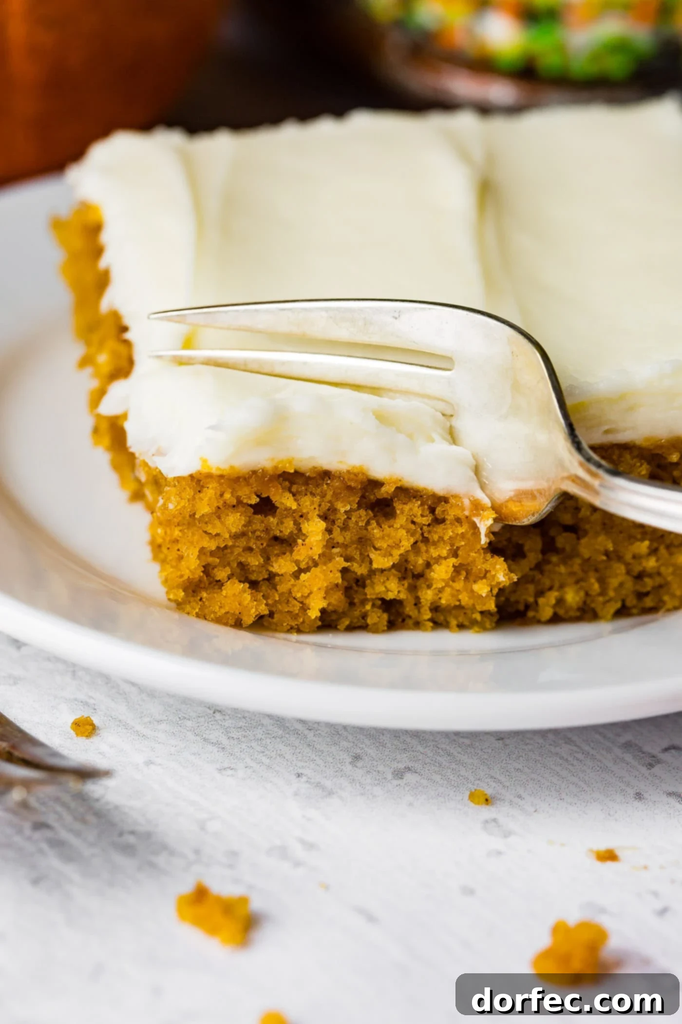 A photo of someone removing a bite of pumpkin sheet cake with a fork.