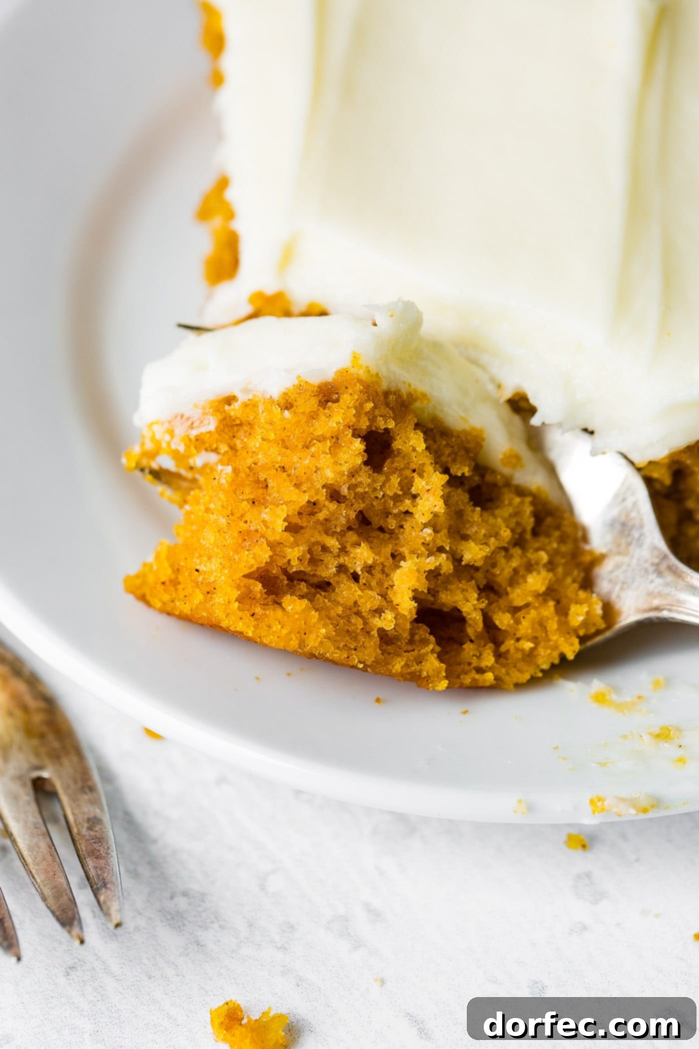 A photo of someone removing a bite of pumpkin sheet cake with a fork.