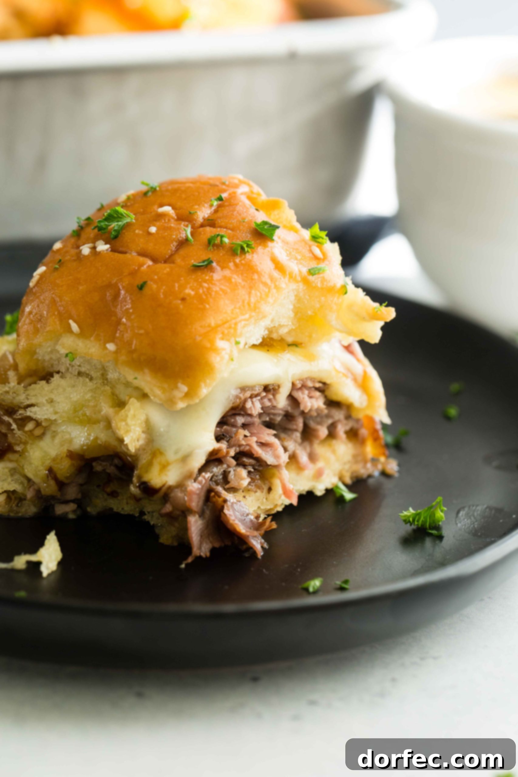 A photo of a single french dip slider on a black plate, ready for dipping.
