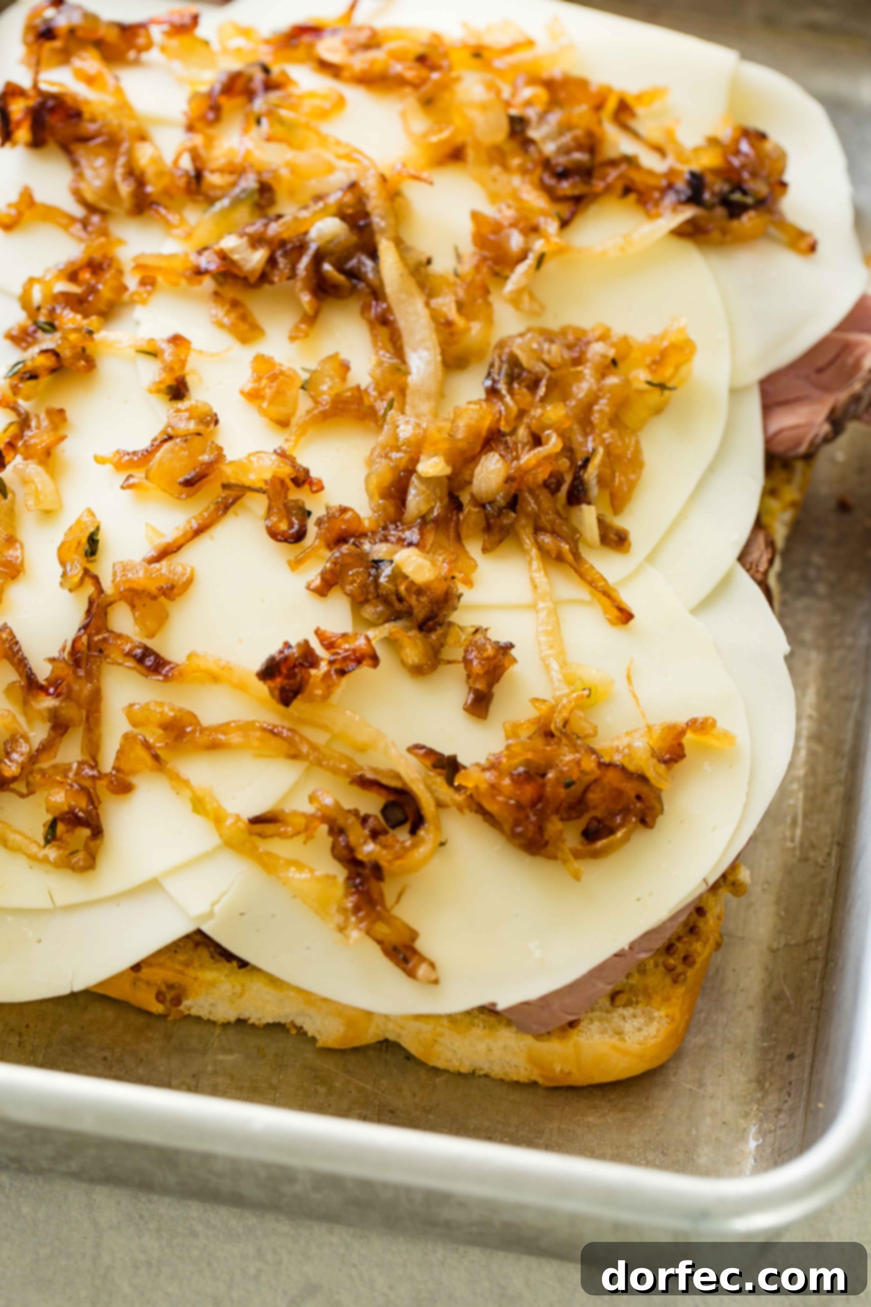 A photo of french sliders being prepared with the caramelized onions added.