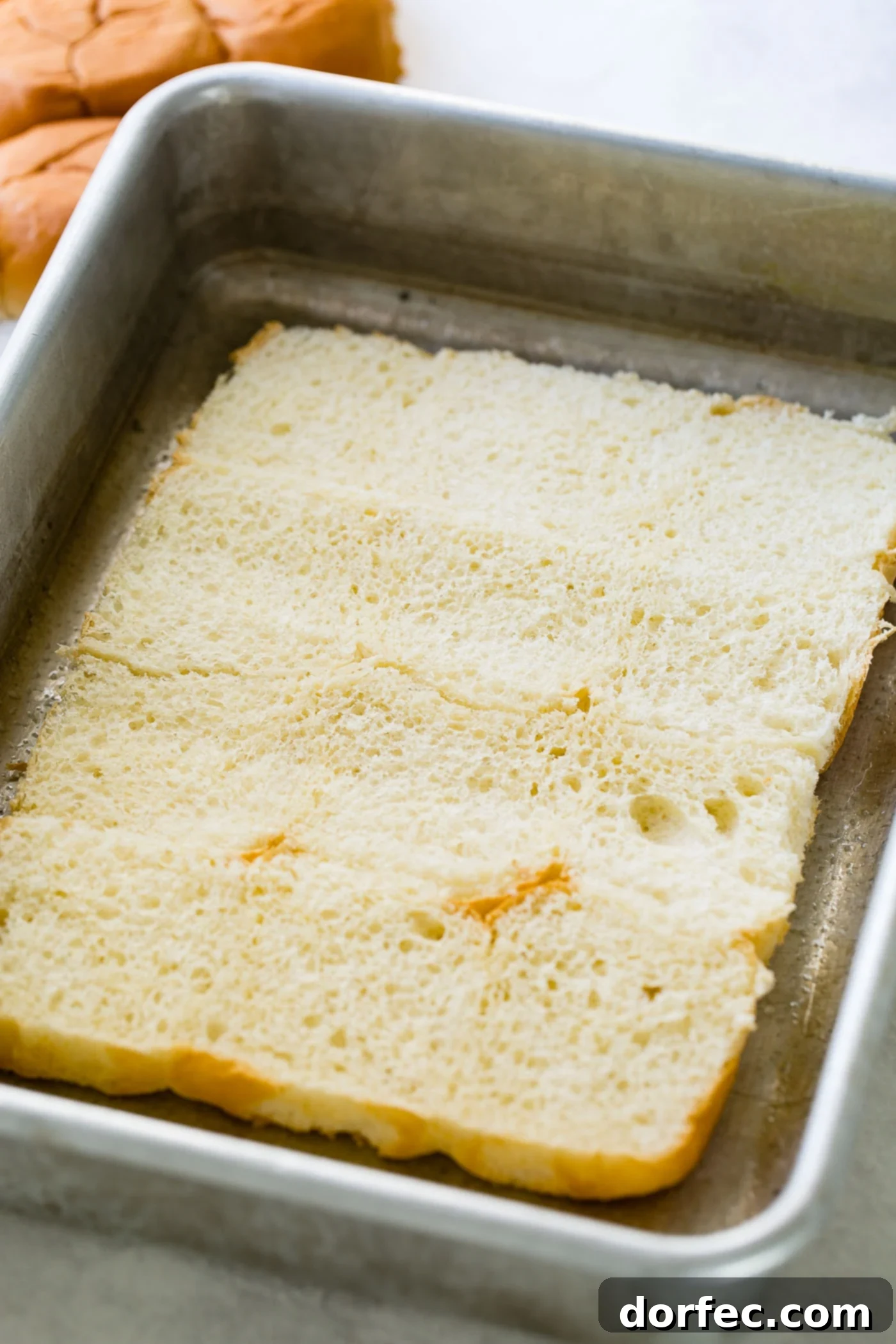 A photo of a layer or slider rolls sliced in half and laying in a pan, ready for assembly.