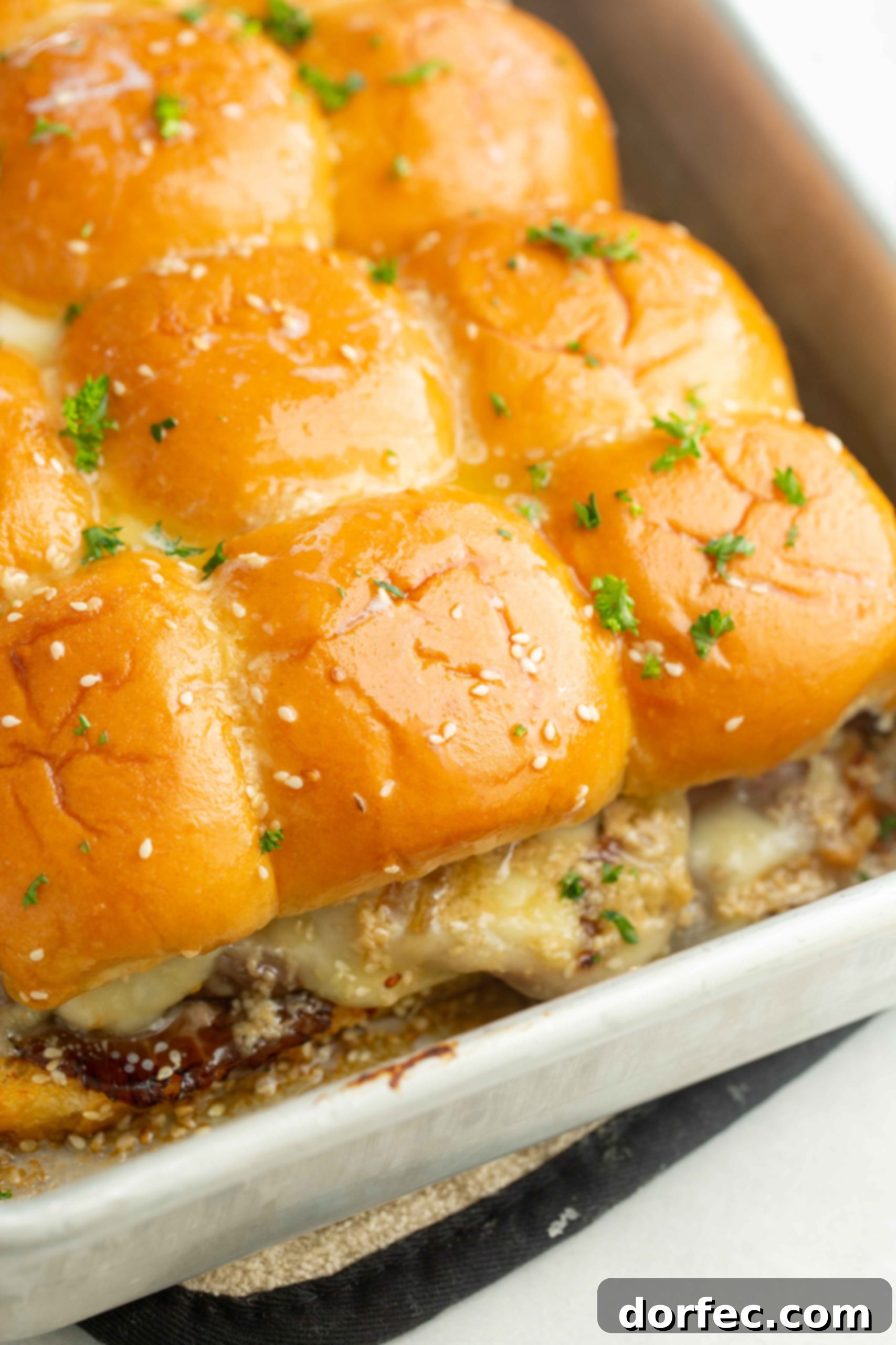 A photo of baked french dip sliders, golden and ready to be served.