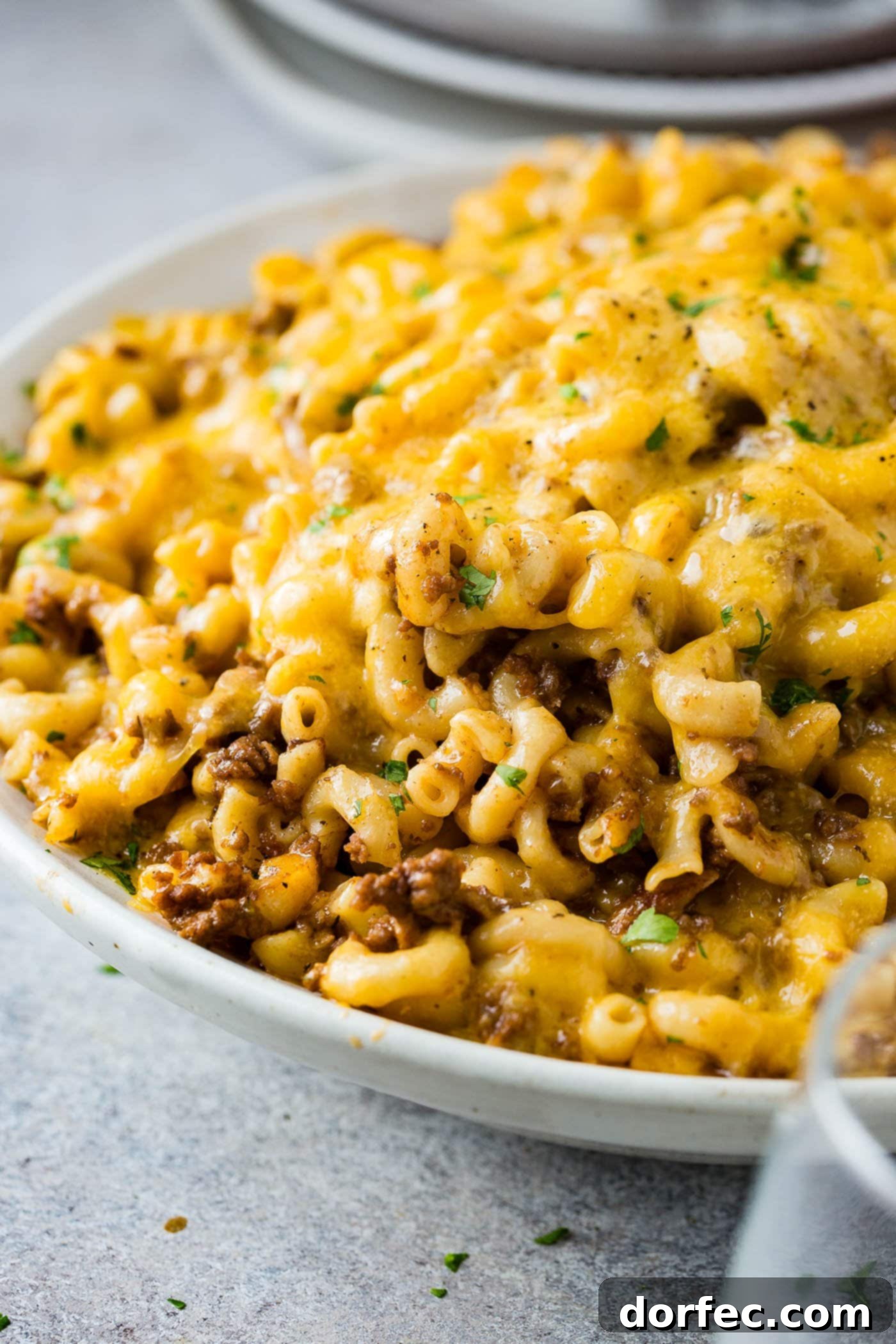 A photo of a white serving bowl full of cheesy Hamburger Helper ready to serve.