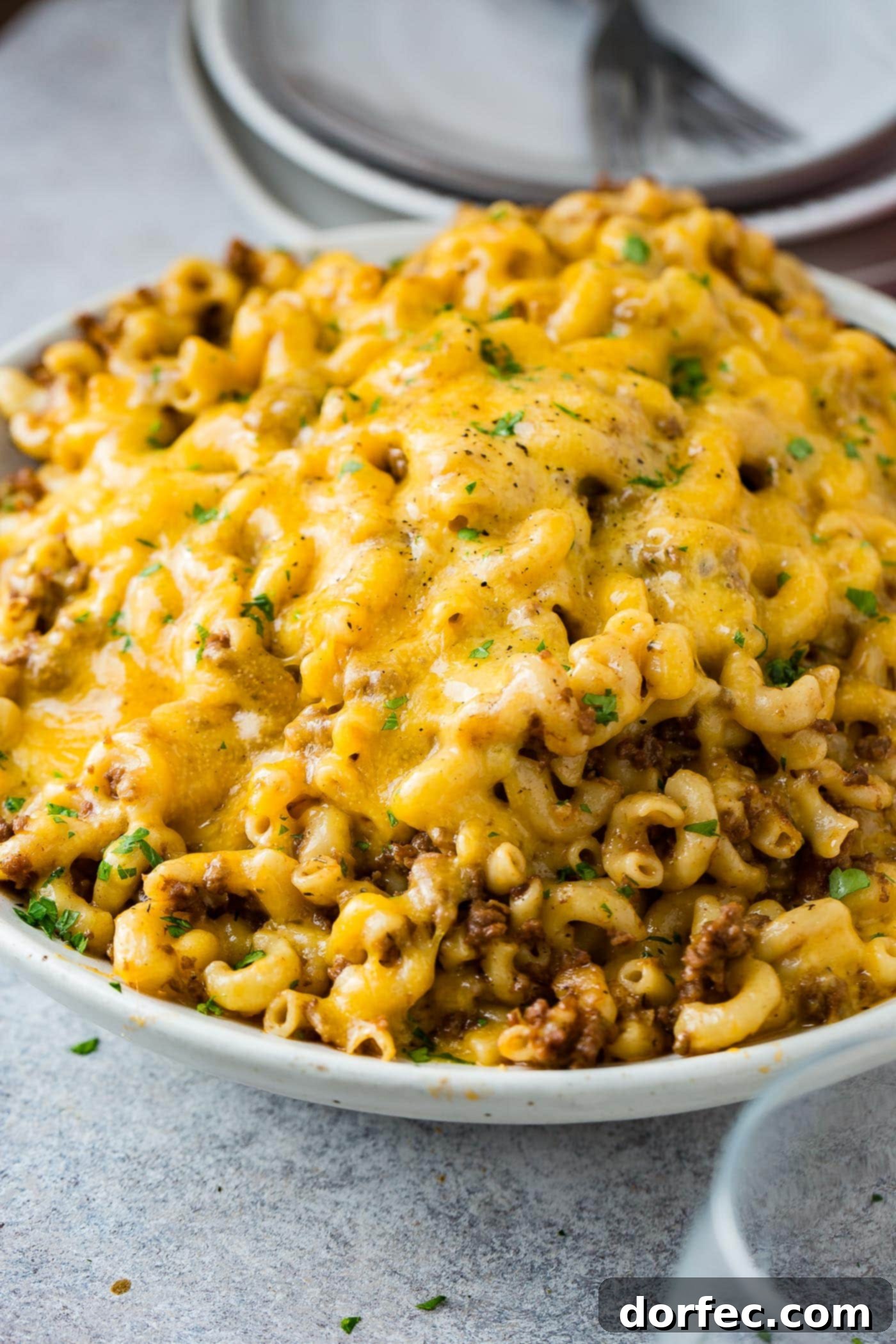 A photo of a white serving bowl full of cheesy Hamburger Helper ready to serve.