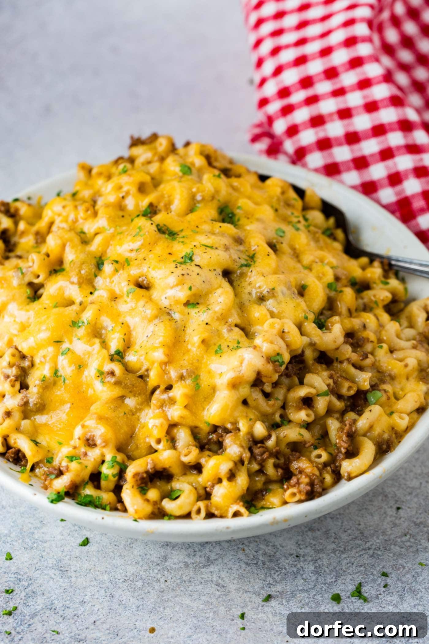 A photo of a white serving bowl full of cheesy Hamburger Helper ready to serve.