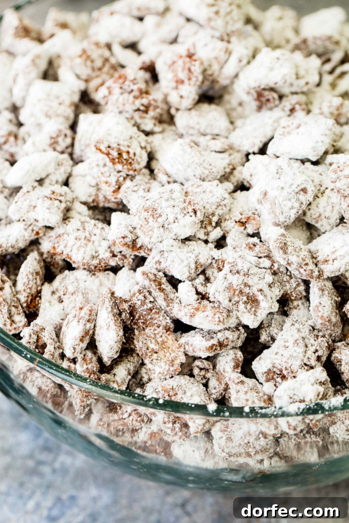 A photo of muddy buddies snack mix in a glass bowl.