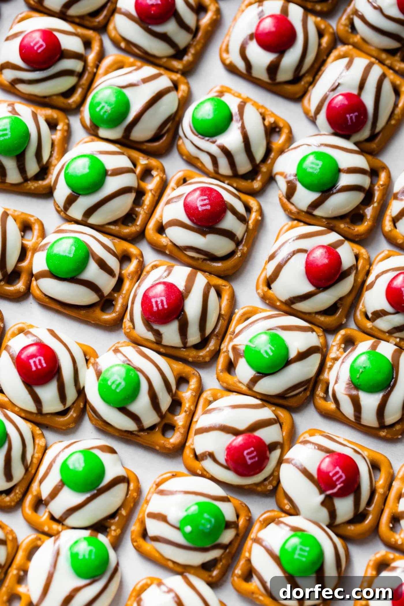 a cookie sheet with lines of christmas m&m pretzel hugs