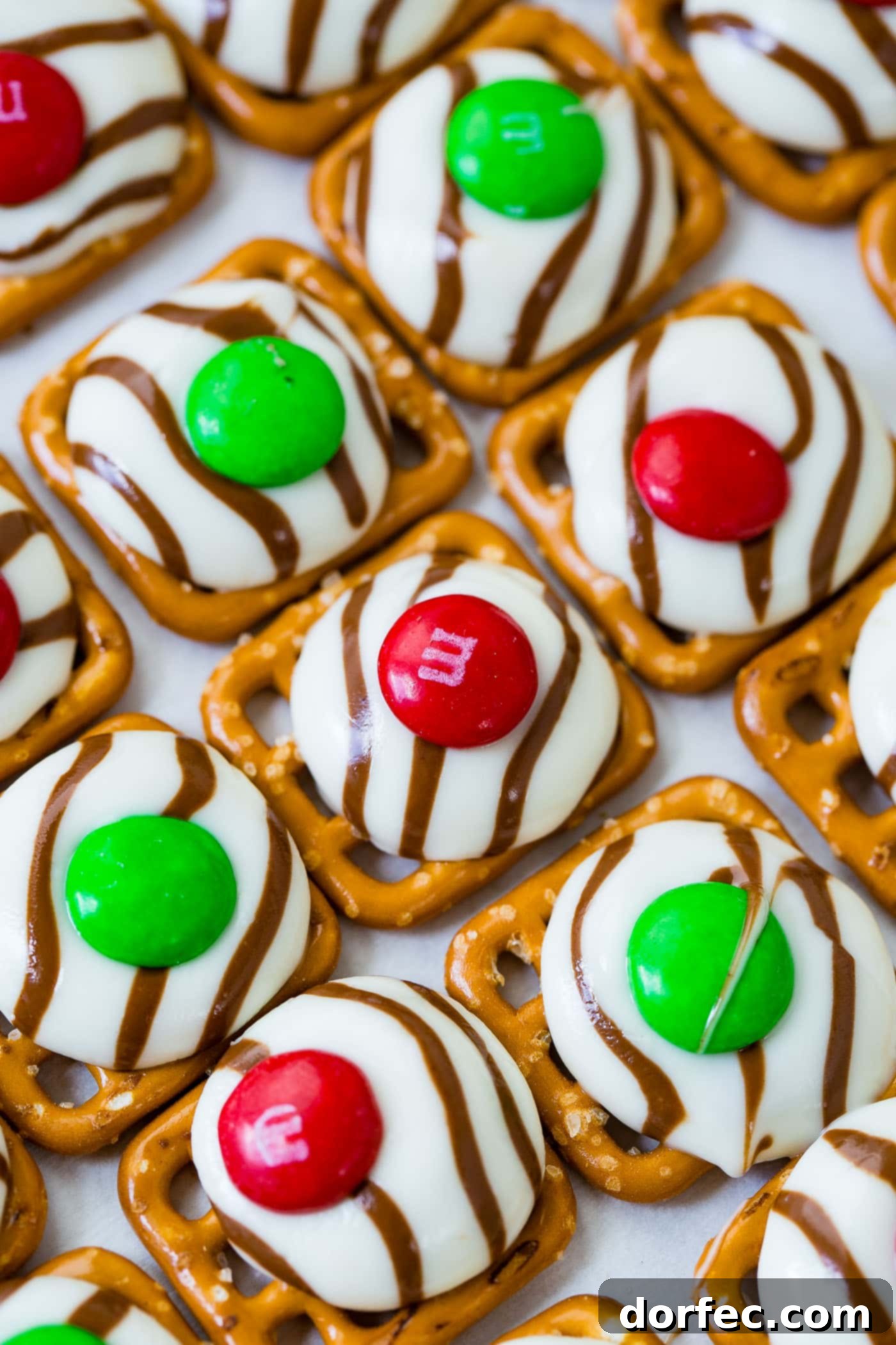 a cookie sheet with lines of christmas m&m pretzel hugs