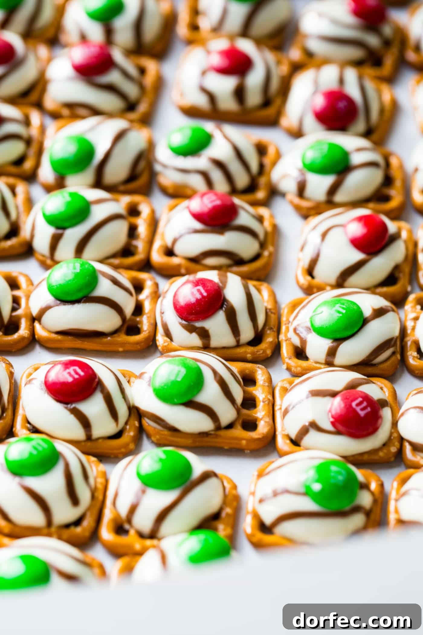 a cookie sheet with lines of christmas m&m pretzel hugs