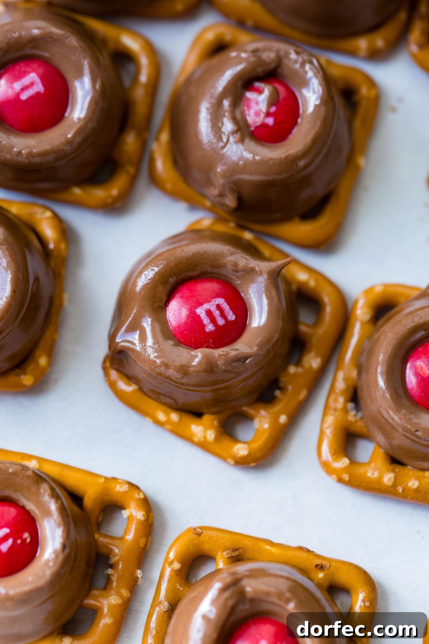 A festive platter showcasing Rolo Pretzel Bites with M&Ms, featuring vibrant red and green candies, elegantly arranged on parchment paper for both charm and easy serving.