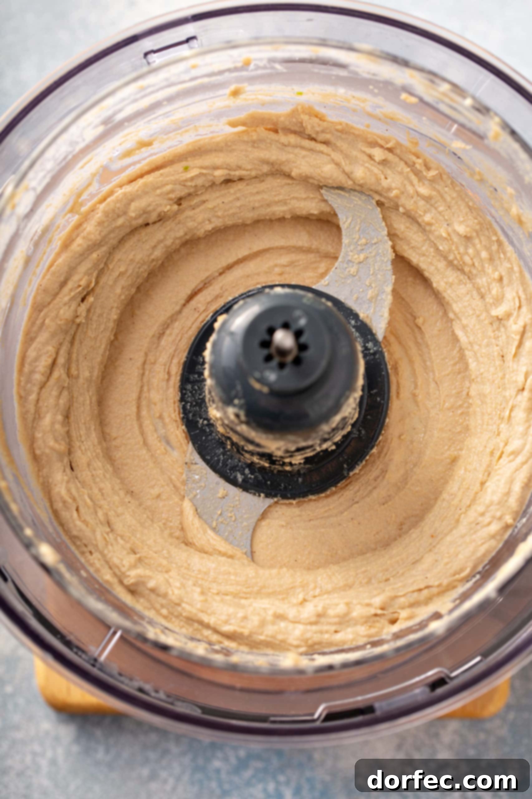 Best Easy Homemade Hummus A food processor with mixed ingredients for homemade hummus.
