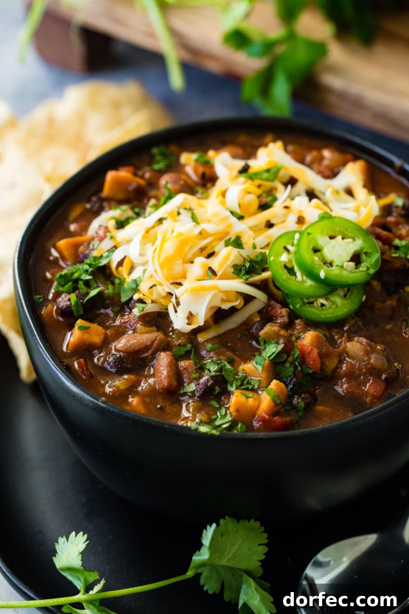 Instant Pot Vegetarian Chili A steaming bowl of Instant Pot vegetarian chili, garnished with a generous sprinkle of shredded cheese and vibrant slices of fresh jalapeño, highlighting its rich texture and inviting warmth.
