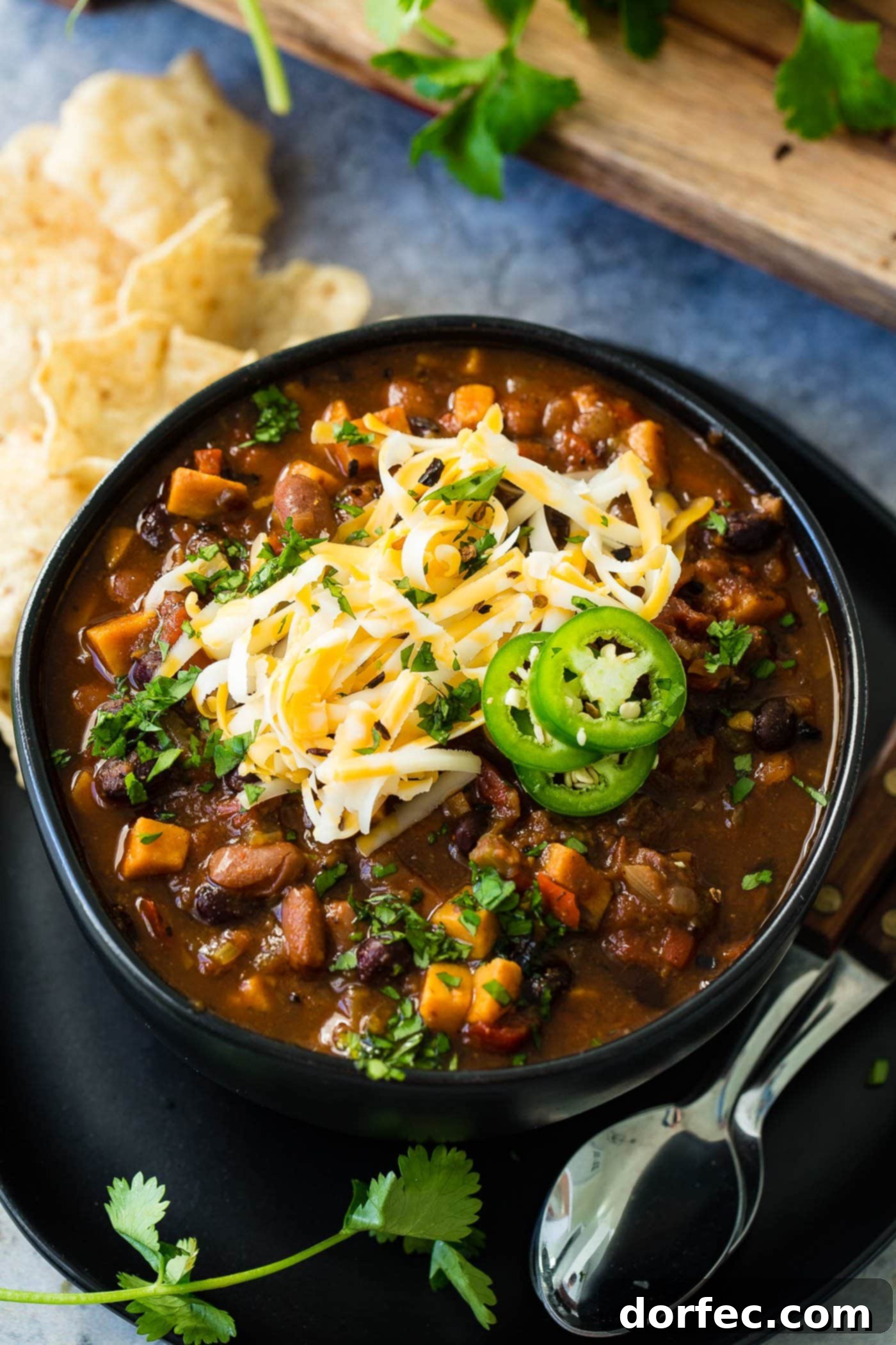 Instant Pot Vegetarian Chili A close-up shot of a rustic bowl filled with steaming Instant Pot vegetarian chili, richly textured with beans and vegetables, topped with melted shredded cheese and bright green jalapeño slices, ready to be enjoyed.