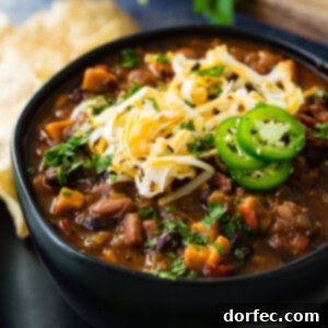 A vibrant bowl of Instant Pot vegetarian chili, garnished with shredded cheese and fresh jalapeño, captured from an overhead view.