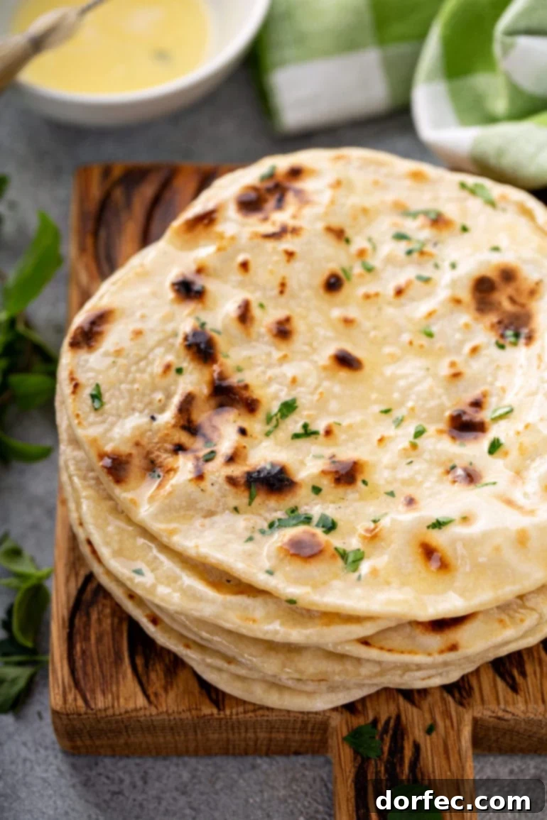 A stack of freshly cooked unleavened bread discs, garnished with chopped fresh herbs, ready to be served.
