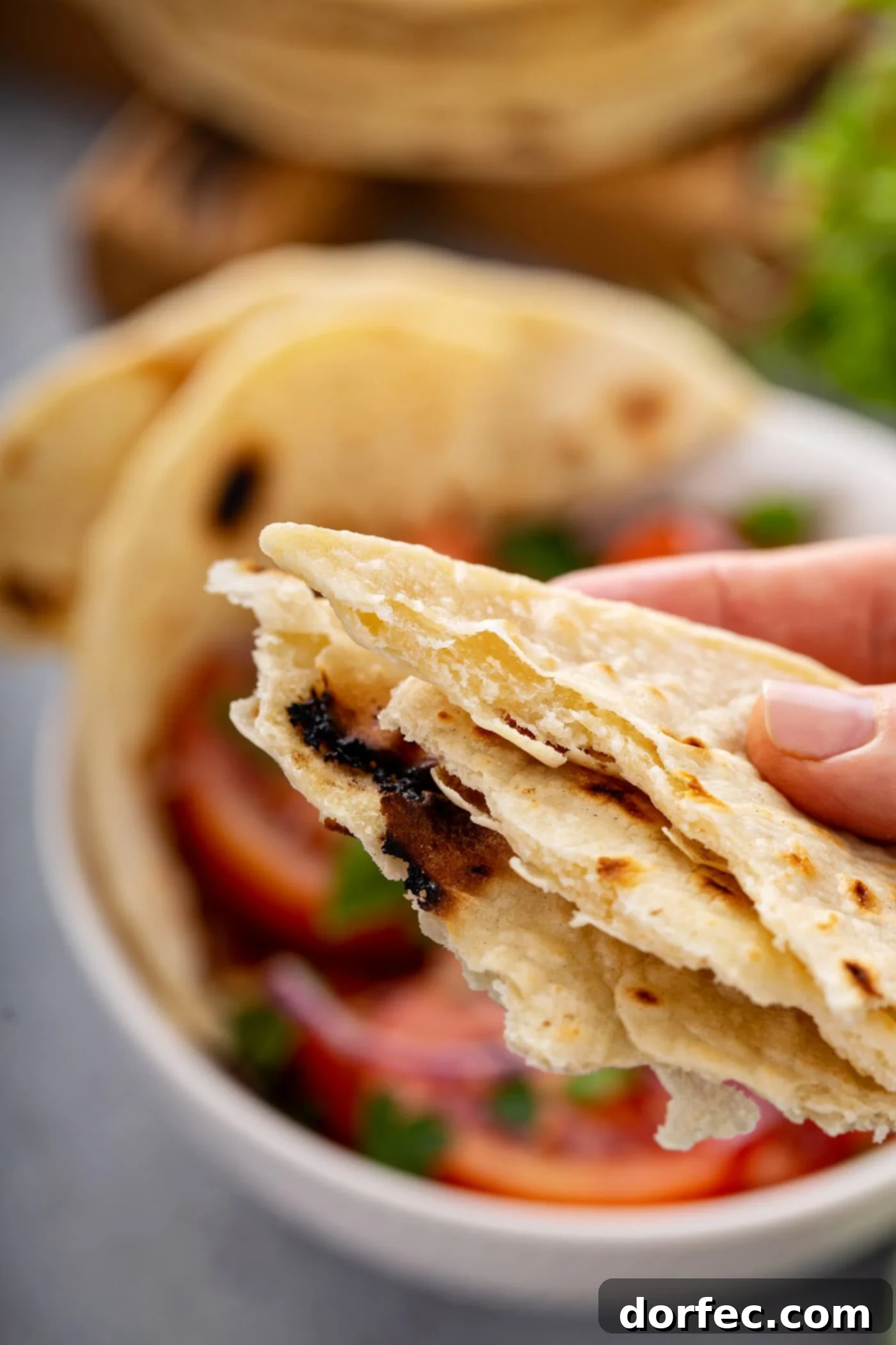 Hands holding torn pieces of warm unleavened bread, inviting you to taste.