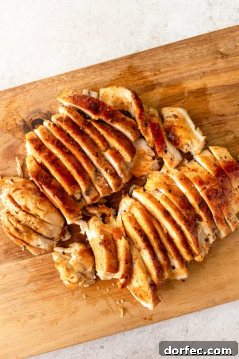 Zesty Lemon Basil Chicken Pasta 3 A close-up photo of golden cooked chicken breasts, perfectly sliced and arranged on a rustic wooden cutting board.