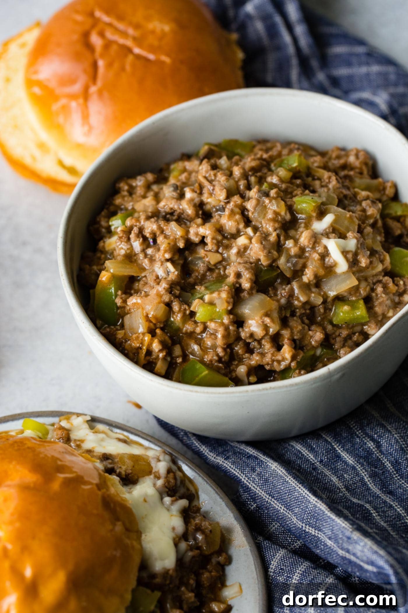Philly Cheesesteak Sloppy Joes A photo of the philly cheesesteak sloppy joe mixture in a white bowl, rich with ground beef, peppers, and onions, ready to be served on buns.