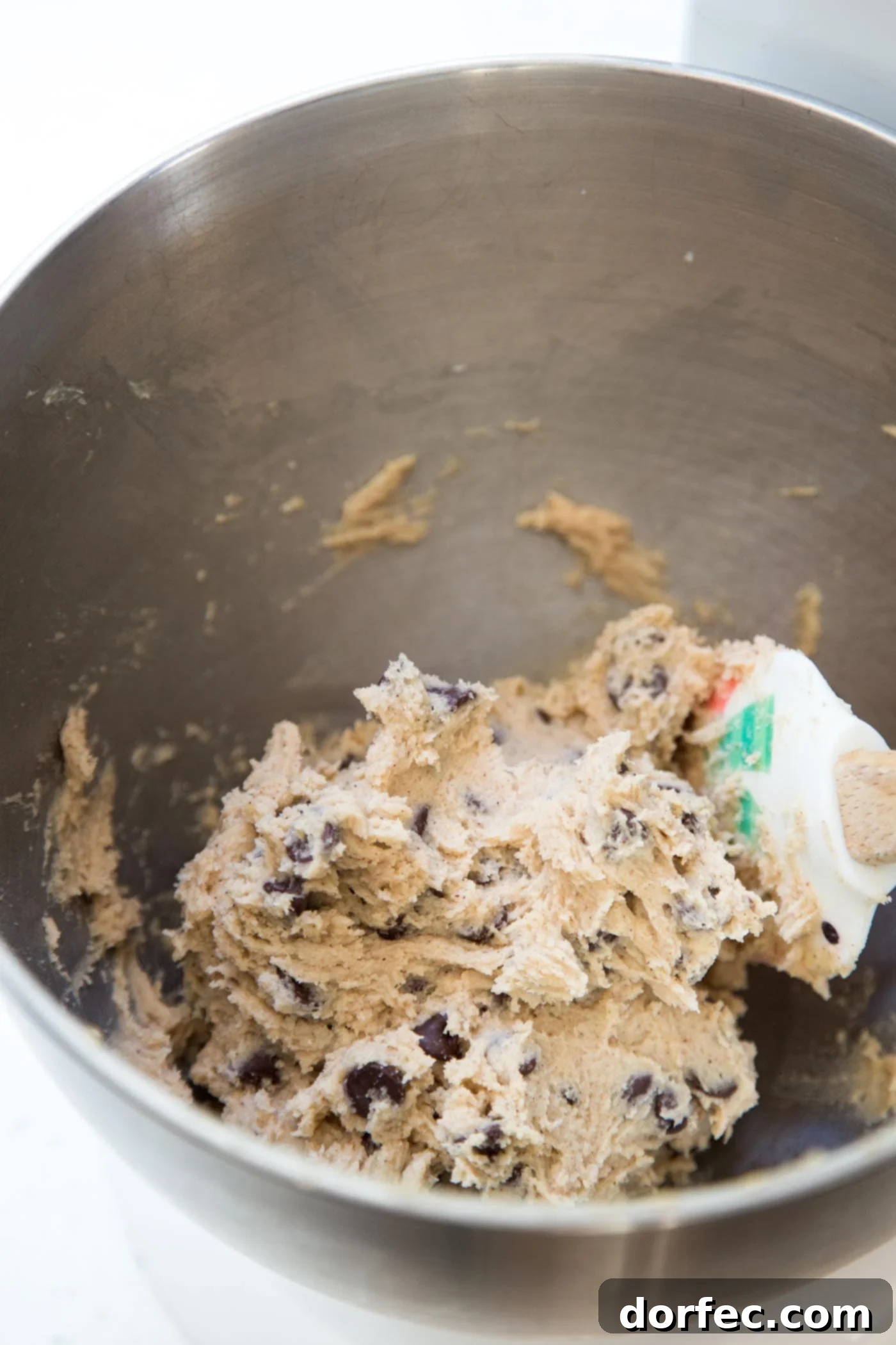 Spiced Chocolate Chip Snickerdoodles 3 Chocolate chip snickerdoodle cookie dough being mixed in a large bowl, showing the consistency and distribution of chocolate chips.