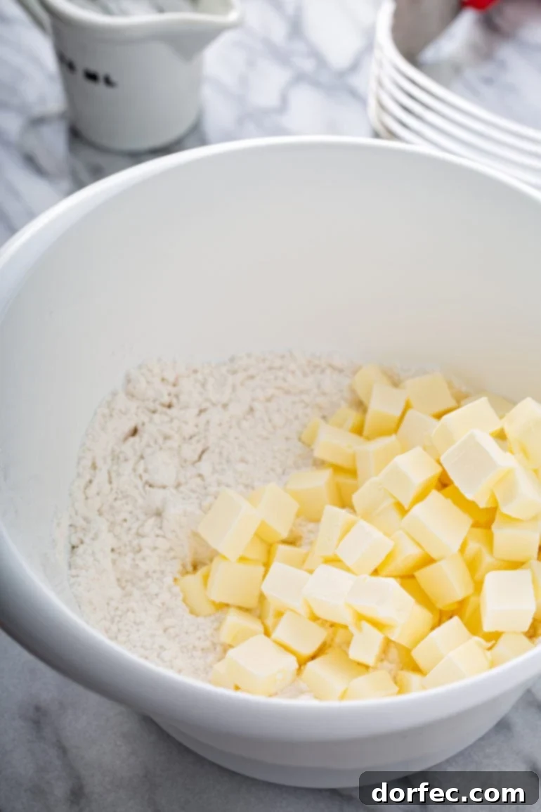 A mixing bowl containing flour and neatly cubed cold butter, illustrating the first step in making pie dough.