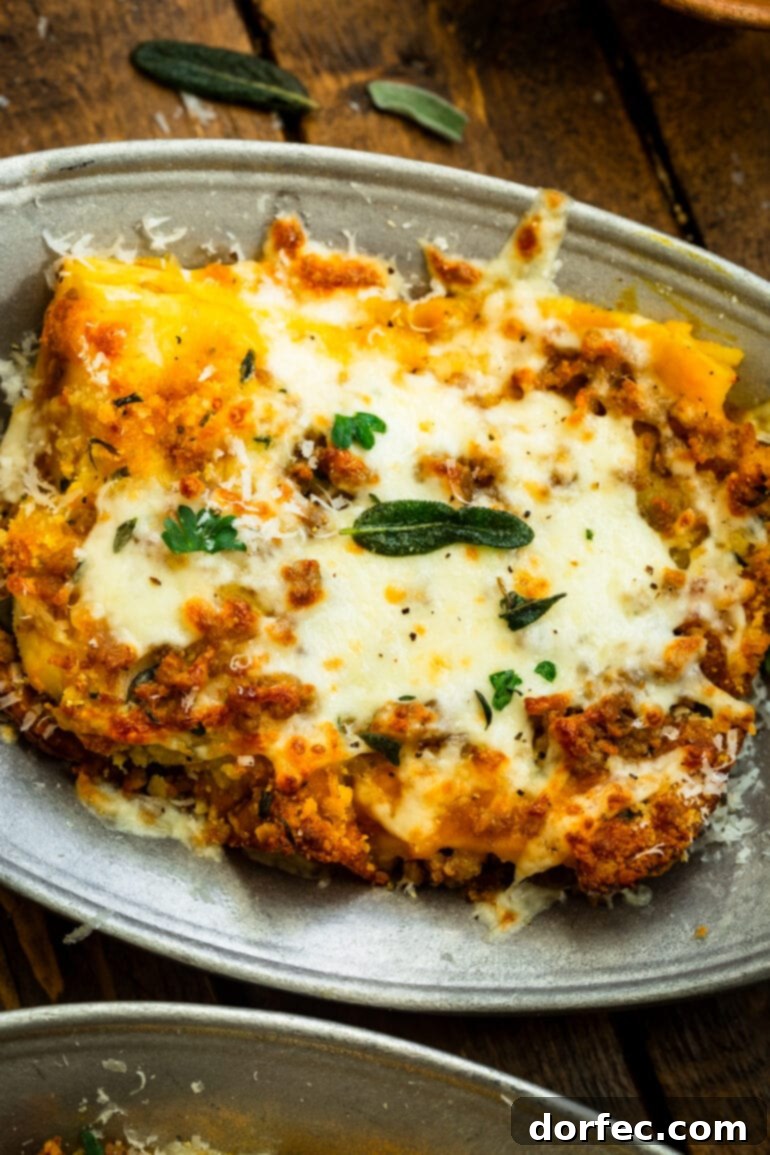 Browned Butter Pork and Butternut Squash Lasagna 3 A perfectly portioned serving of browned butter pork and butternut squash lasagna, adorned with melted cheese and delicate crispy sage leaves, presented on a plate.