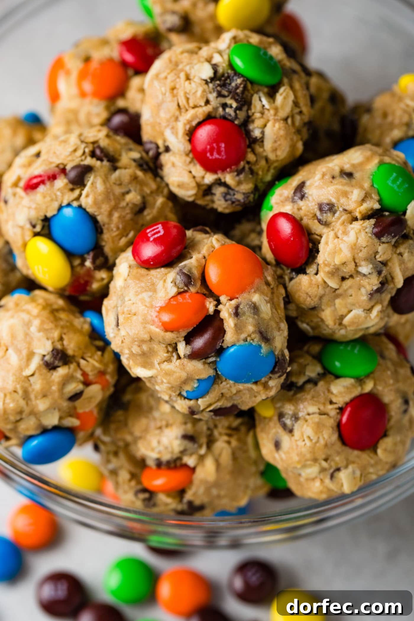 Protein-Packed Peanut Butter Monster Cookie Energy Bites 3 A vibrant bowl full of homemade protein energy balls, showcasing mini M&M's, plump raisins, and tiny chocolate chips embedded in each delicious sphere.