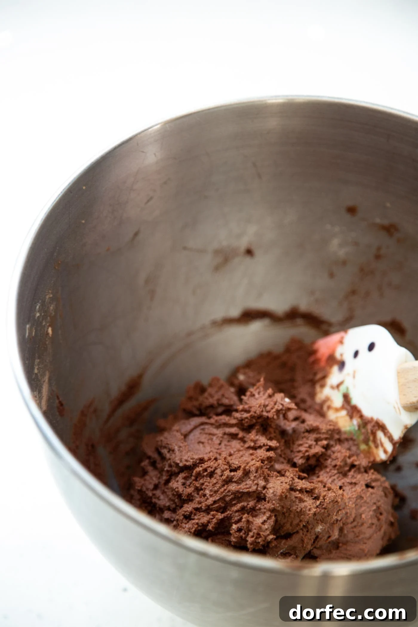Chocolate cookie dough being mixed in a large stainless steel mixing bowl