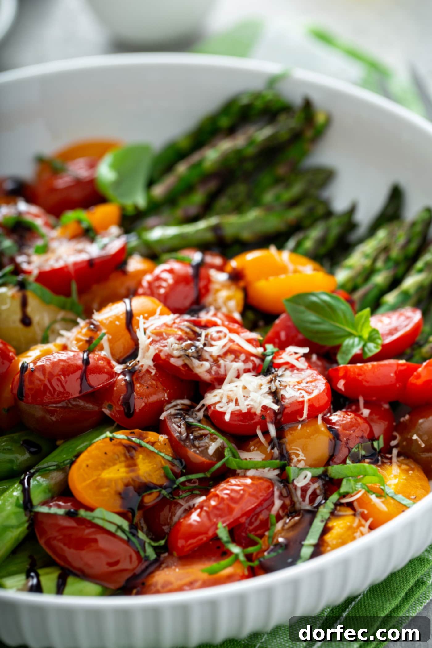 Glossy Balsamic Roasted Tomatoes and Asparagus 2 A close-up picture of glistening balsamic glazed roasted tomatoes and vibrant green asparagus. Sliced red and yellow tomatoes burst with color, perfectly complemented by tender asparagus spears. A generous drizzle of dark balsamic glaze and a delicate dusting of grated Parmesan cheese complete this appetizing, healthy side dish.
