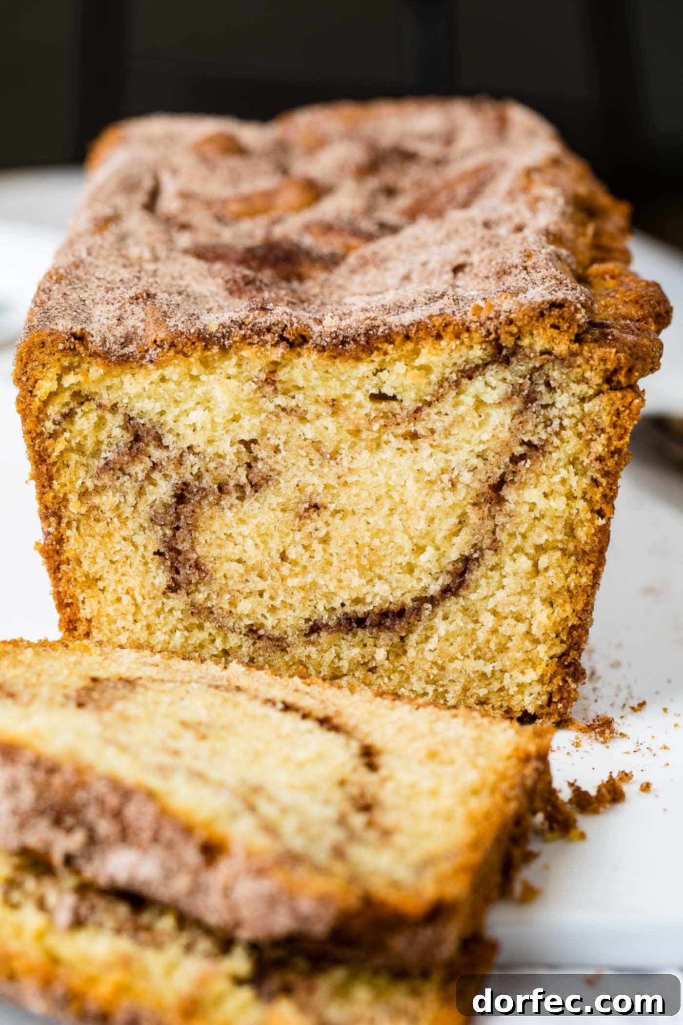Cinnamon Sugar Swirl Loaf 2 A beautifully sliced loaf of Snickerdoodle Bread, revealing a mesmerizing swirl of cinnamon sugar within. The crust is golden-brown and lightly sugared.