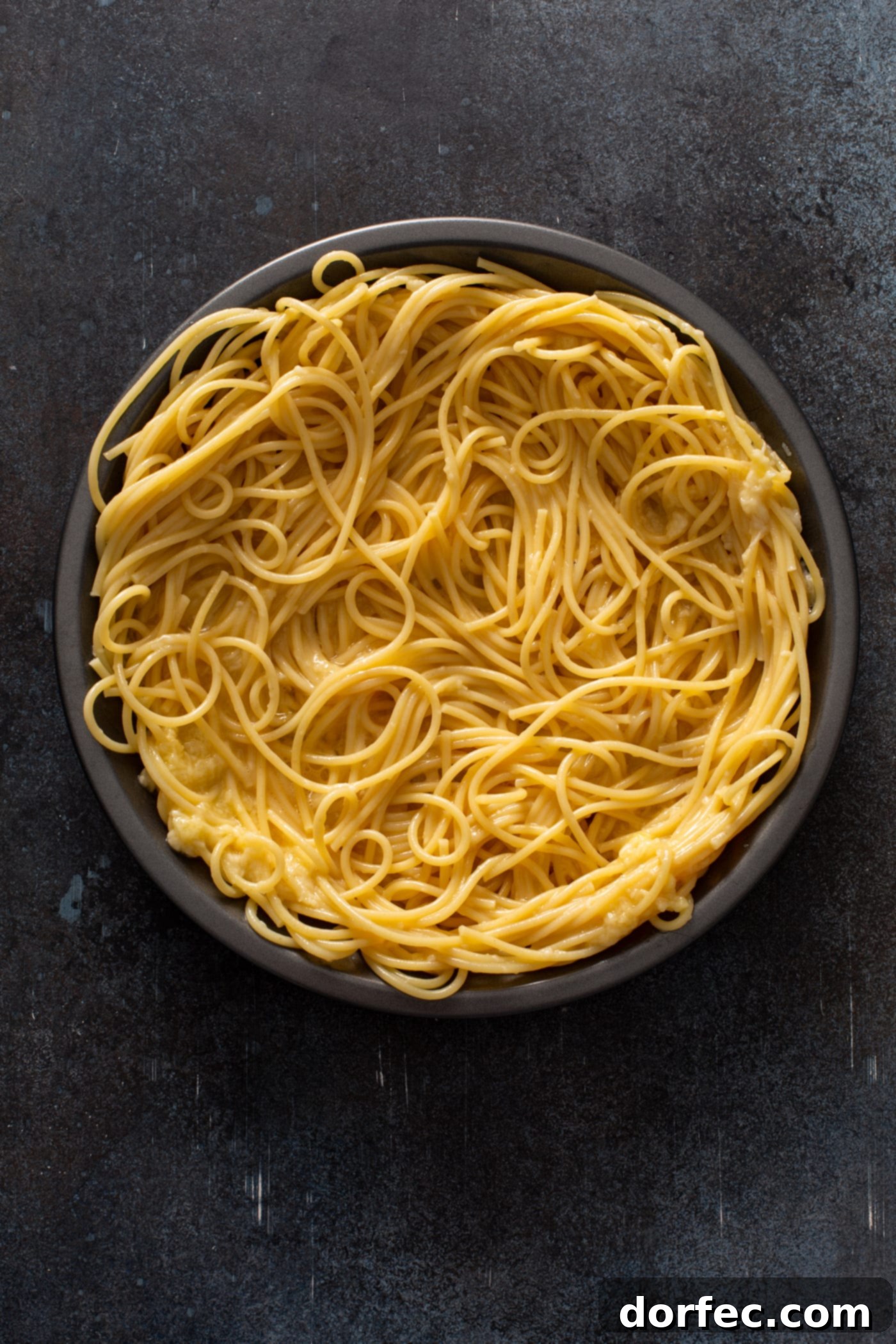 A pie dish filled with cooked spaghetti noodles.