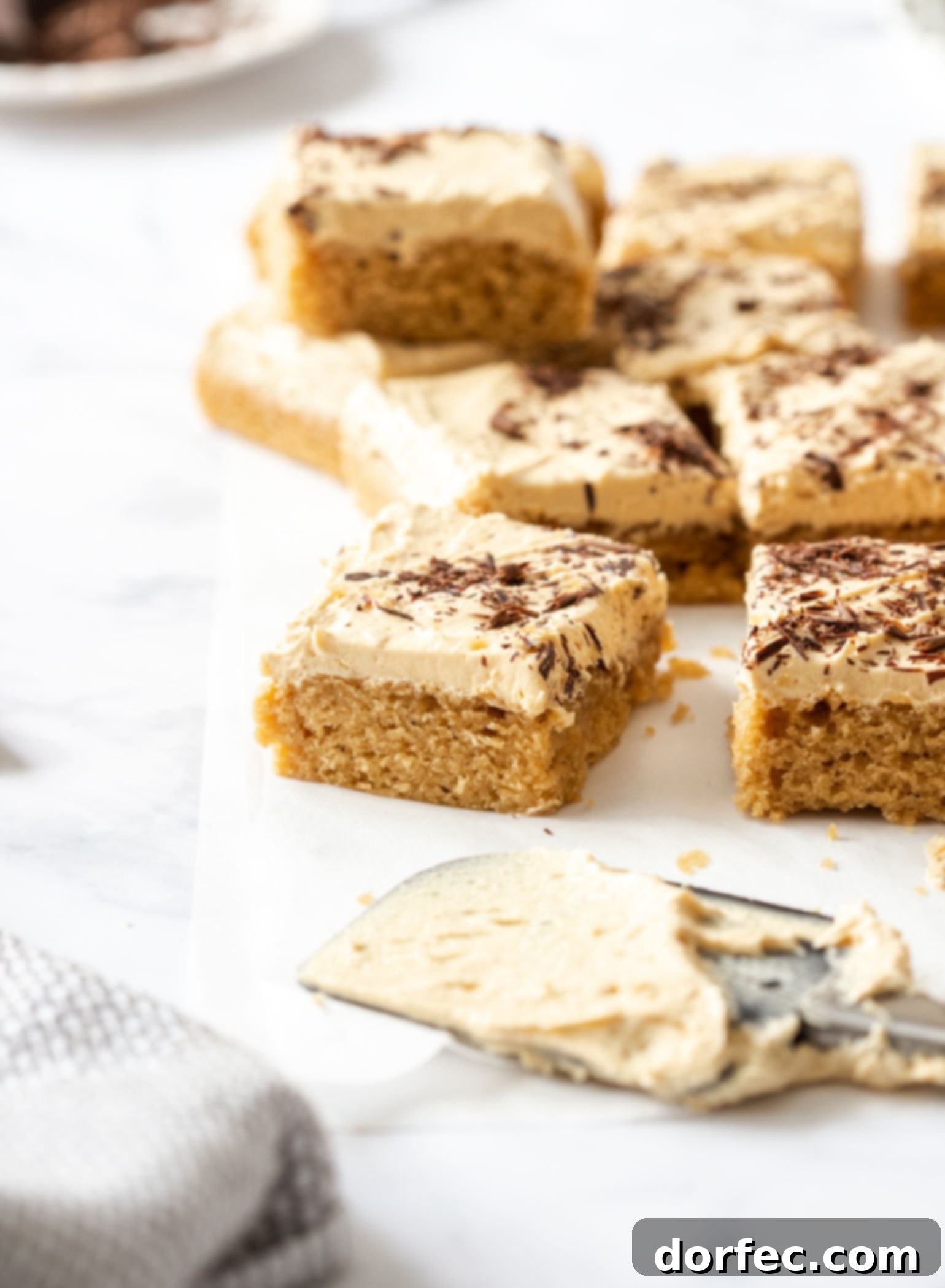 Ultimate Peanut Butter Sheet Cake 6 Several slices of the delicious Peanut Butter Sheet Cake arranged neatly on a sheet of baking paper, highlighting its inviting layers and perfect frosting.