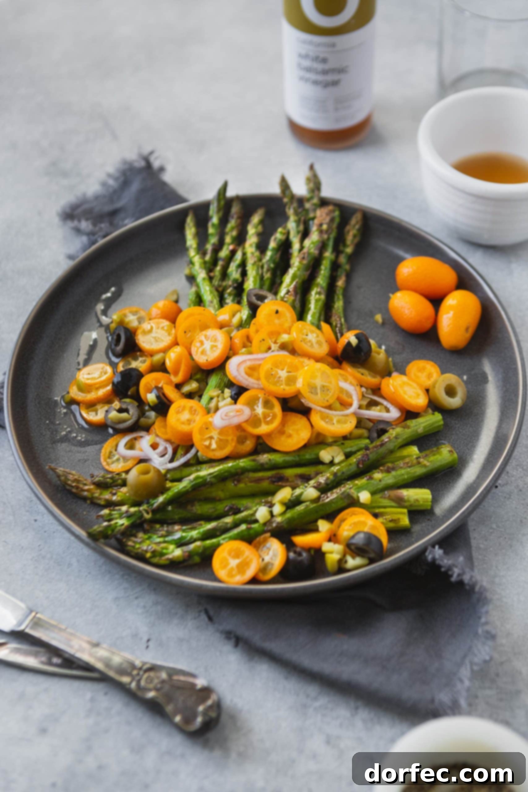 A close-up of a serving of roasted asparagus with kumquats, showcasing the bright colors and fresh ingredients on a elegant serving dish.