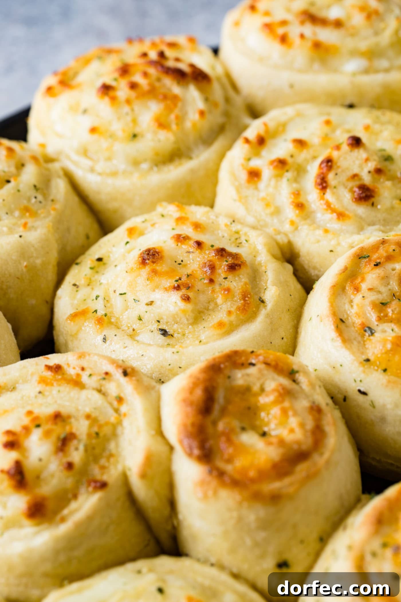A pan of golden brown baked cheese pizza rolls. The cheese doodles are like cinnamon rolls filled with mozzarella cheese.