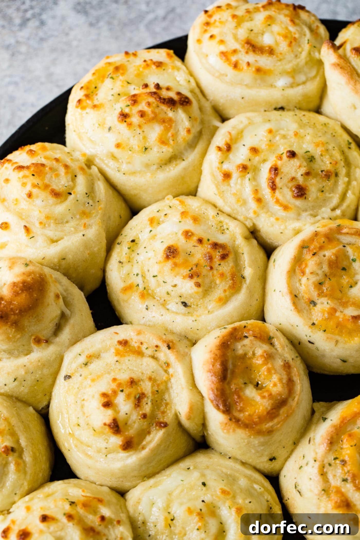 A pan full of baked cheese pizza rolls. The rolls are swirled like cinnamon rolls and are baked to a golden brown.