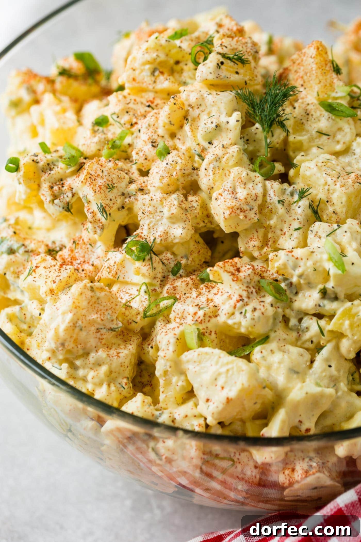 The Only Potato Salad Recipe You'll Ever Need 6 A glass serving bowl of potato salad. The chunks of potato, pickles, and eggs are topped with sprinkled paprika and fresh parsley.