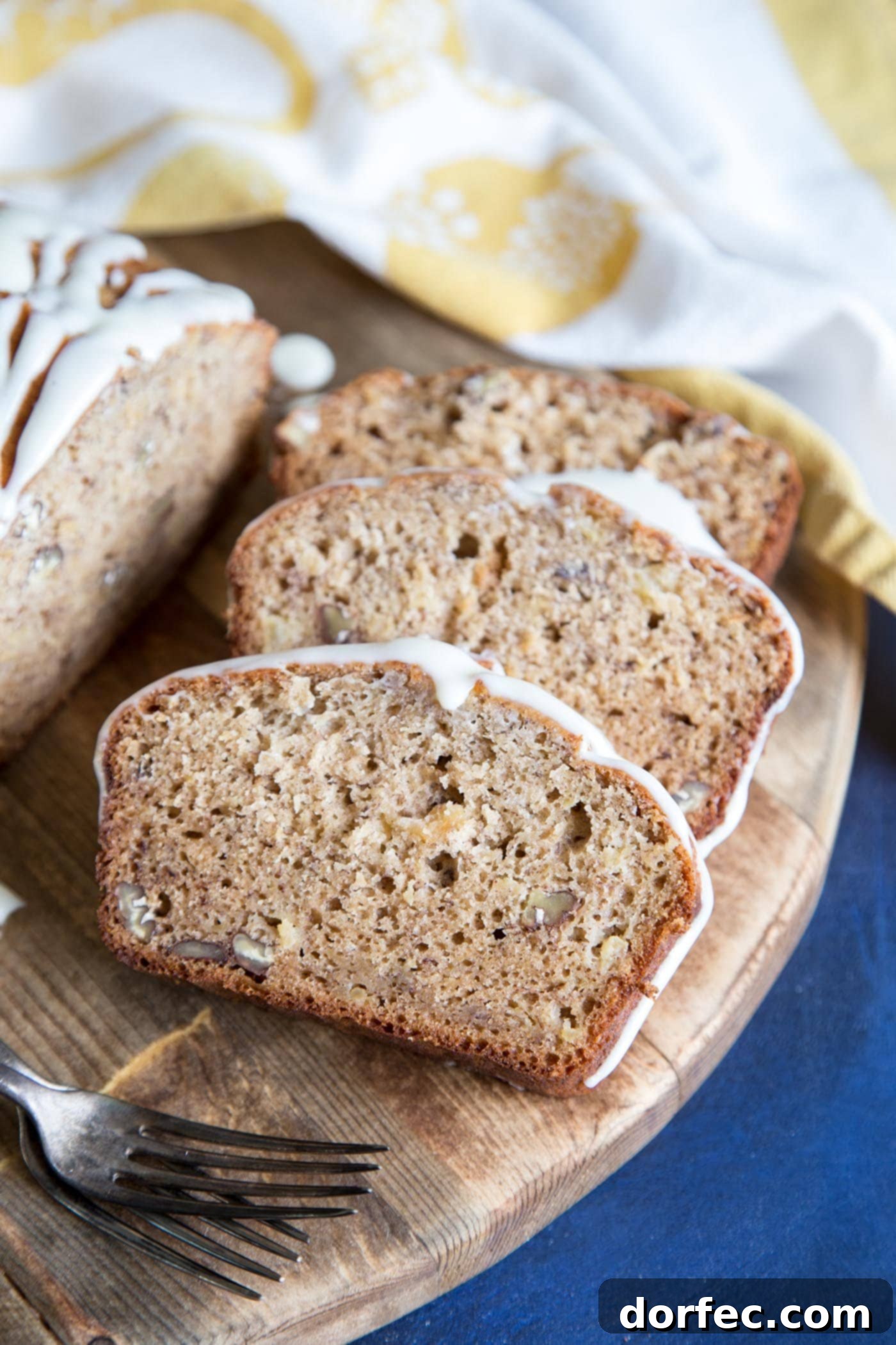 Slices of Hummingbird Cake Banana Bread on a cutting board, drizzled with cream cheese glaze, ready to be served.