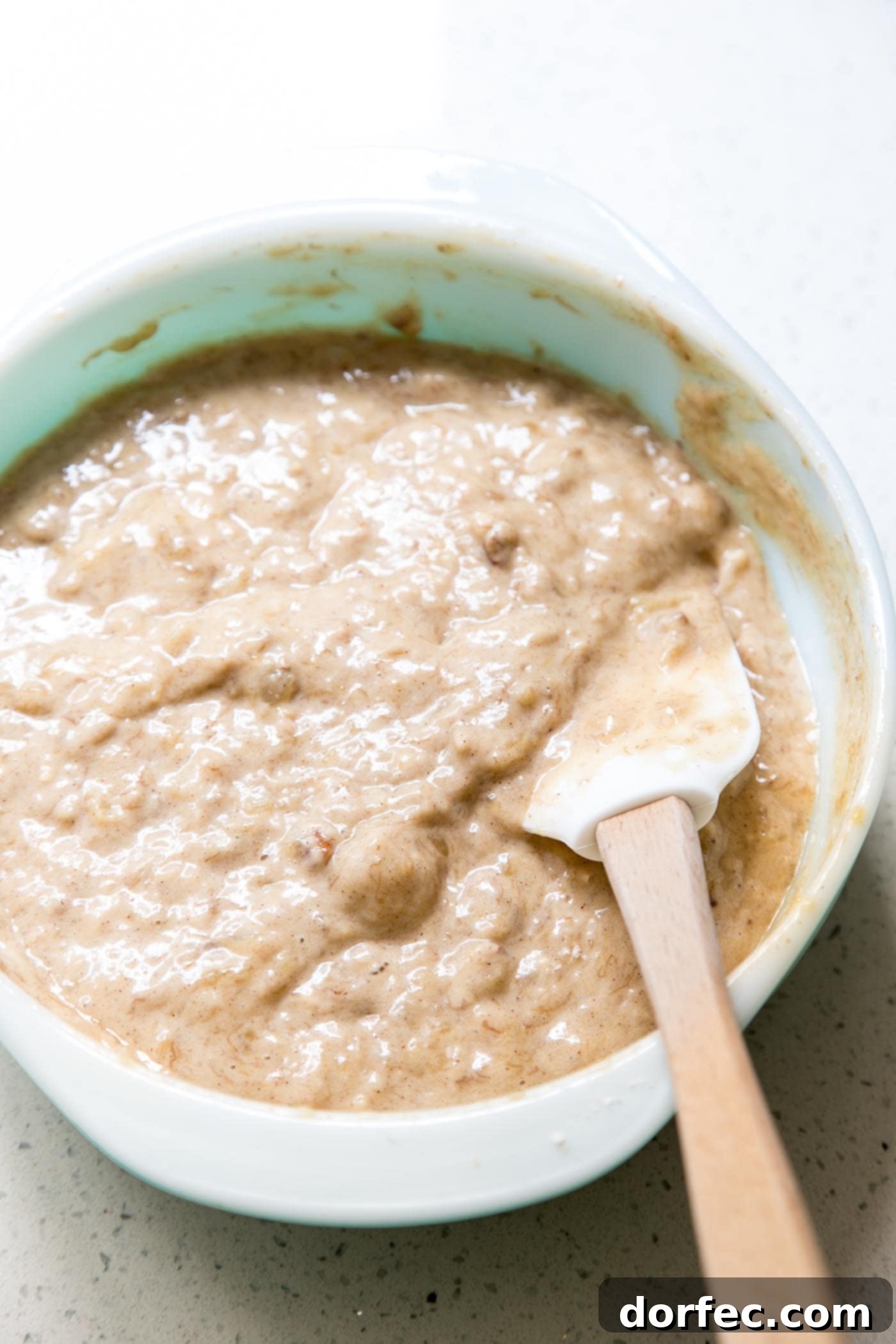 Hummingbird Cake Banana Bread batter being mixed in a large bowl, showcasing the mashed bananas, pineapple, and spices.