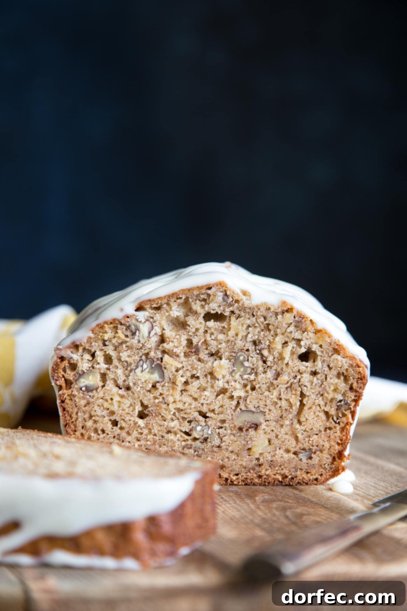 A beautiful cross-section of Hummingbird Cake Banana Bread, highlighting its moist crumb, visible bits of pineapple, and chopped pecans.