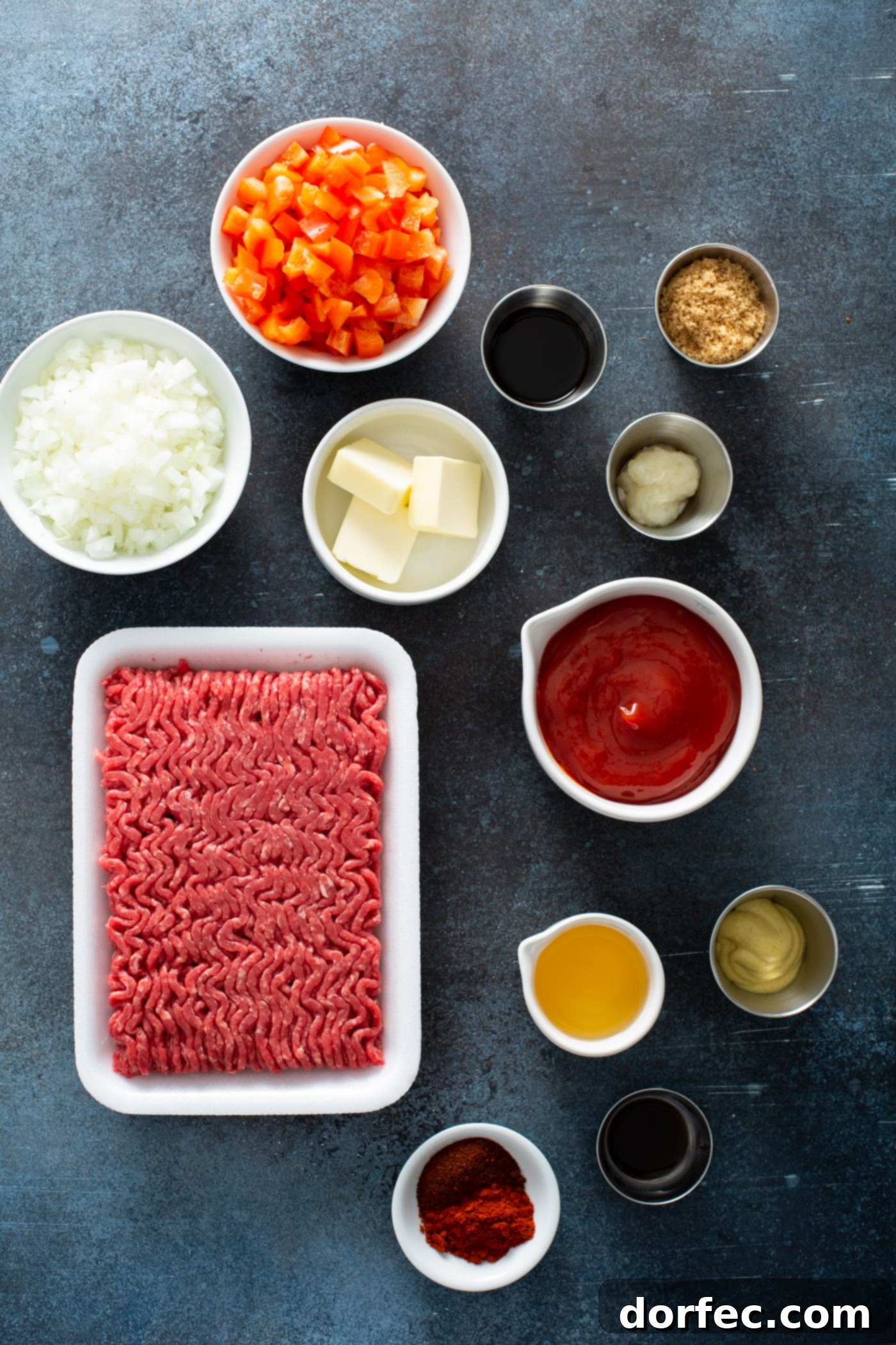 Instant Pot Sloppy Joes Ingredients to make instant pot sloppy joes. There is ground beef, dijon mustard, ketchup, butter, brown sugar, onions, chopped red bell peppers, Worcestershire sauce in small containers.