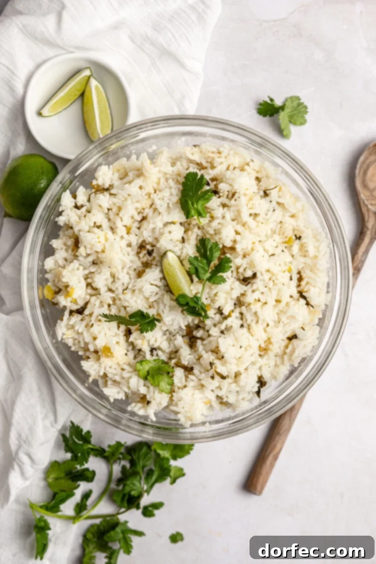 A large glass serving bowl full of fluffy cilantro lime rice, garnished with fresh cilantro and a lime wedge, ready to be served.