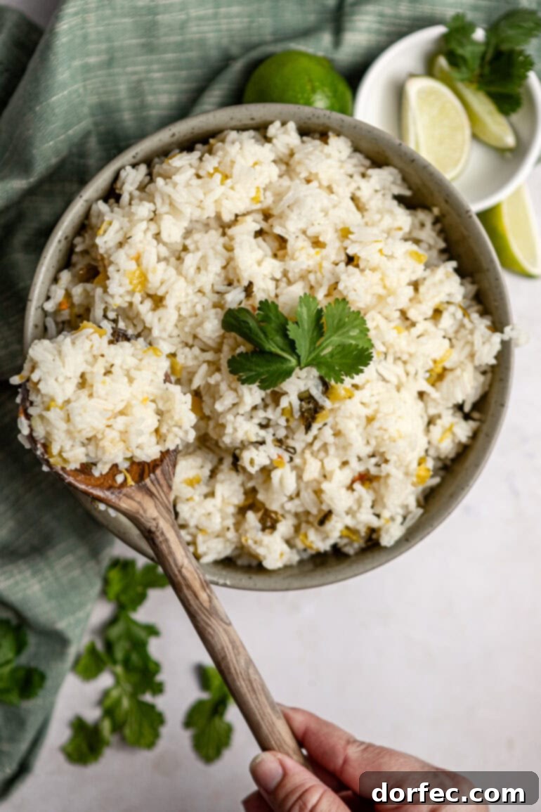 A large serving bowl filled with fluffy cilantro lime rice, with a wooden spoon scooping out a generous portion, highlighting its inviting texture.
